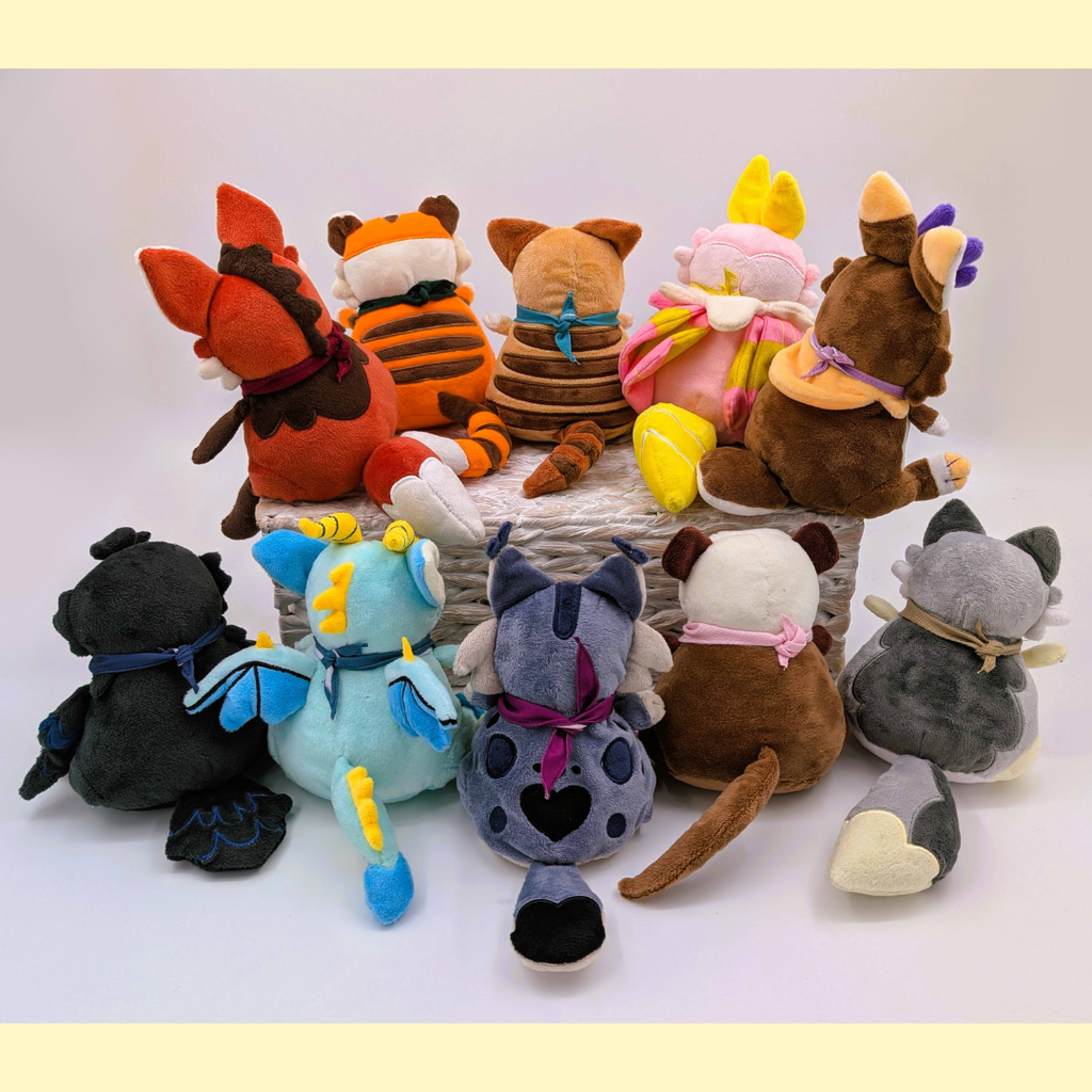 Collection of colorful plush toys arranged on a white surface with a light yellow background.