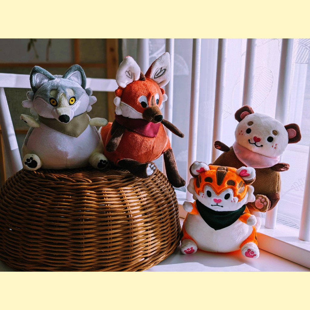 Four plush toys of a wolf, maned wolf, otter, and tiger on a woven basket.