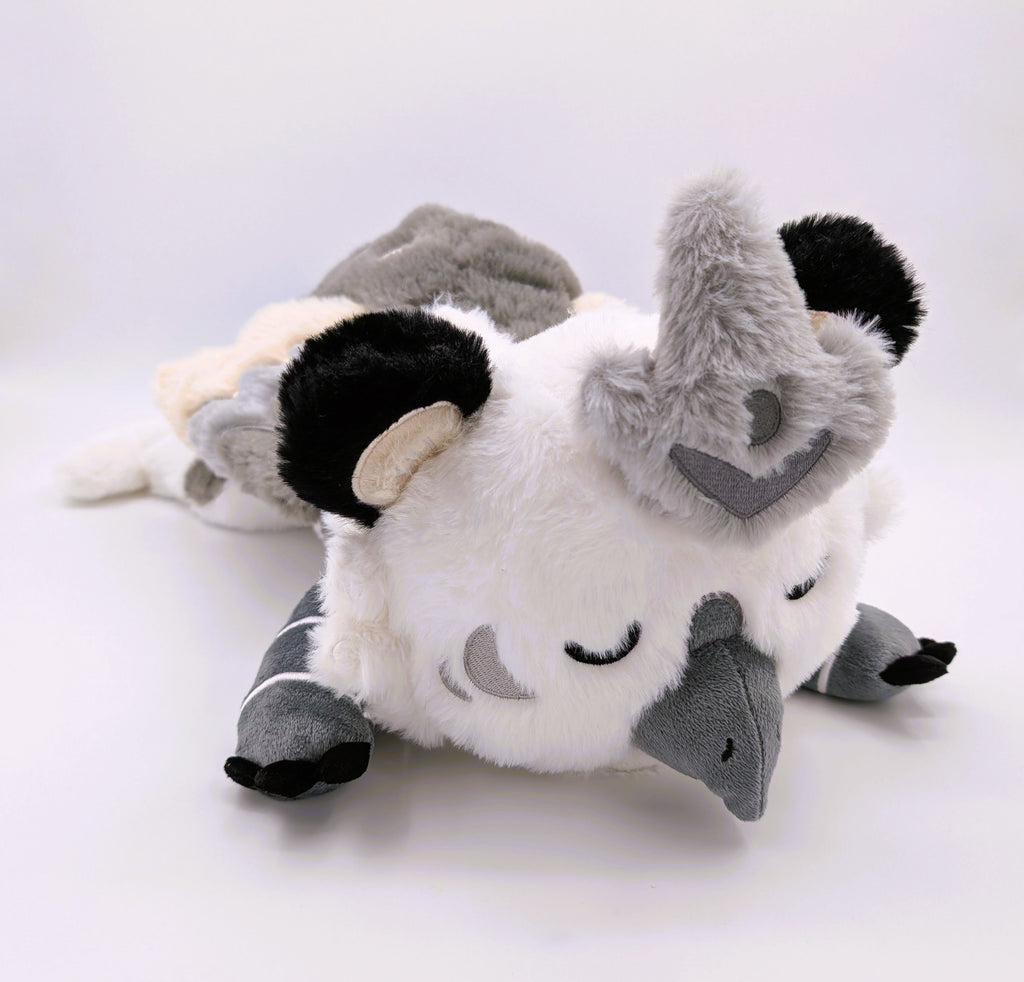 Weighted plush toy of Sesame the grey and white gryphon with his eyes closed 
