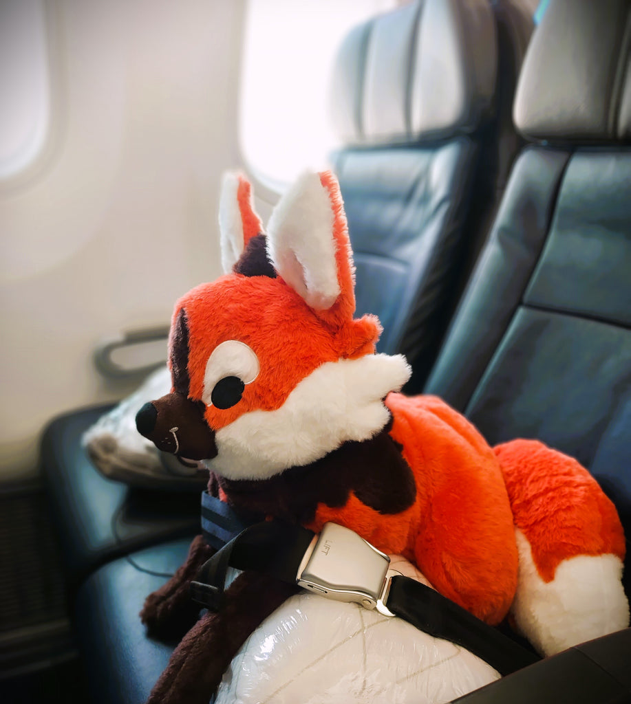 Plush toy of Paprika the maned wolf buckled up in an airplane seat