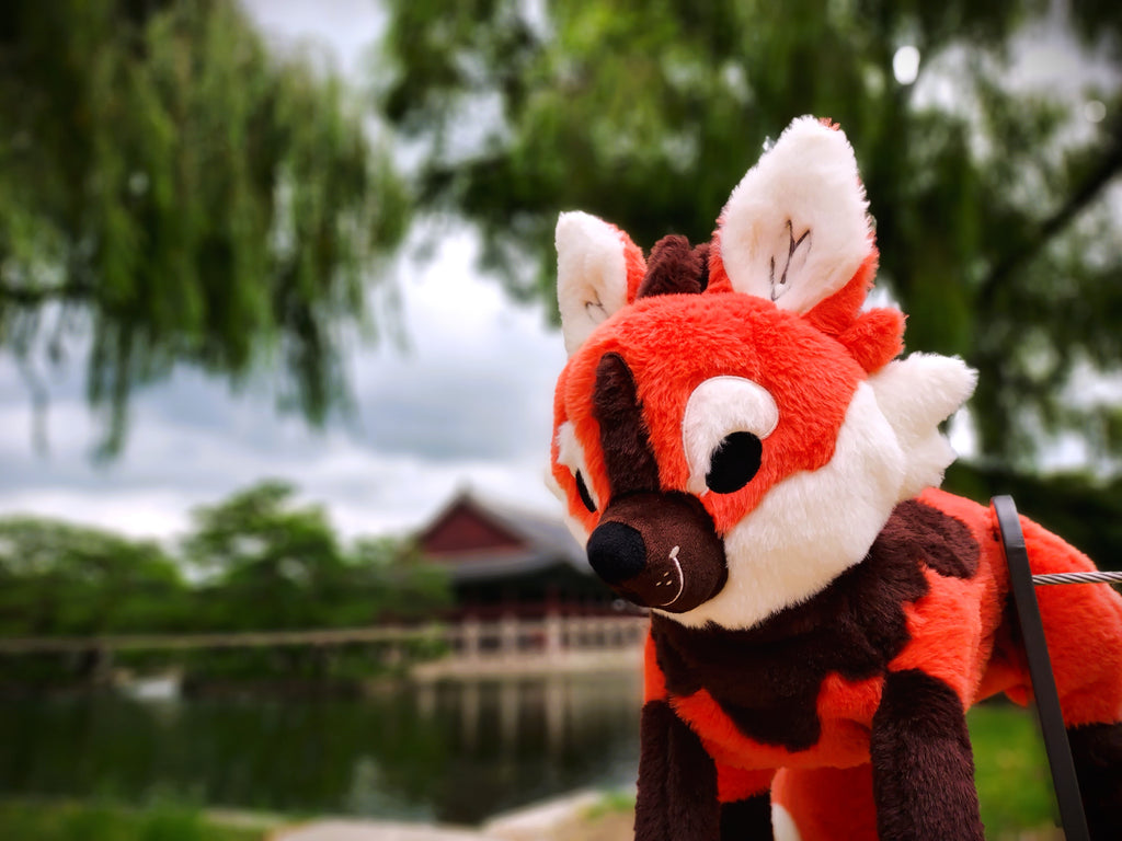 Plush toy of Paprika the maned wolf with trees in the background