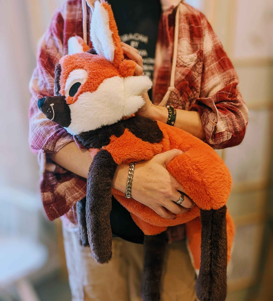 Plush toy of Paprika the maned wolf being held by a person