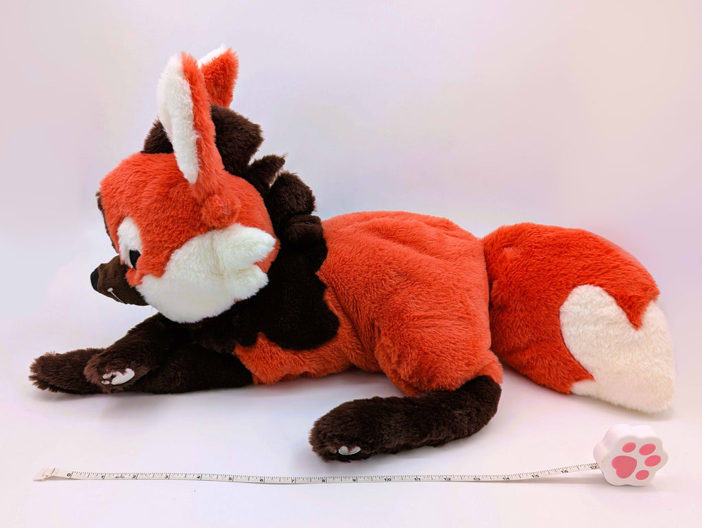 Side view of a plush toy of Paprika the maned wolf with a measuring tape