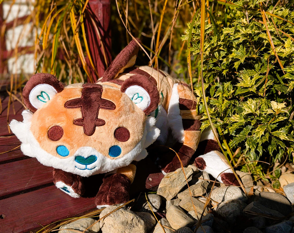 Plush toy of Cornflakes the Tiger and Shark hybrid lying on a bridge in the sun