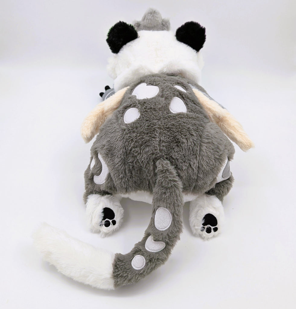 Back view of a weighted plush toy of Sesame the grey and white gryphon 
