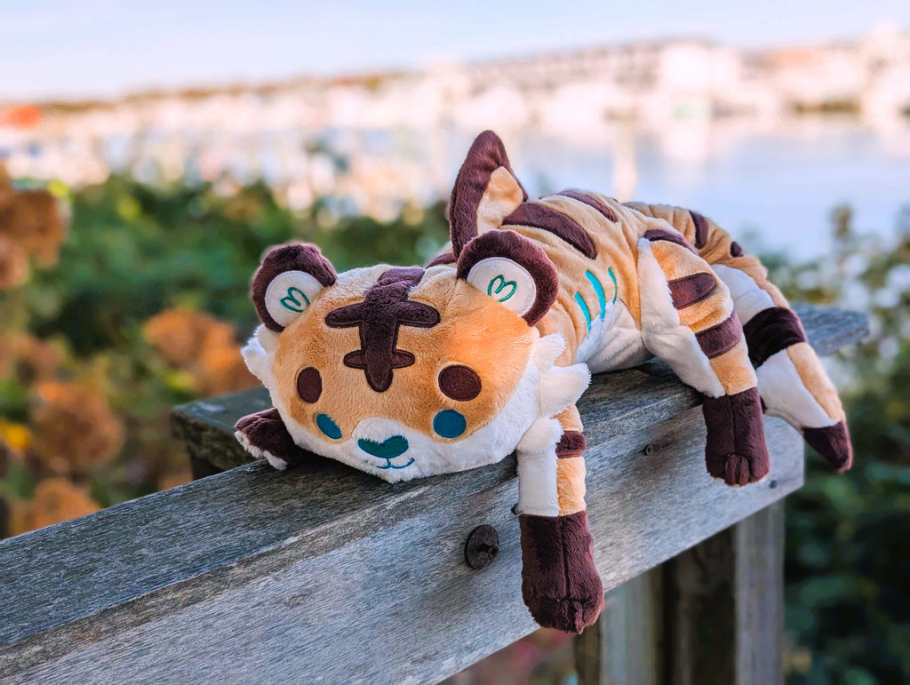 Plush toy of Cornflakes the tiger and shark hybrid resting on a wooden railing