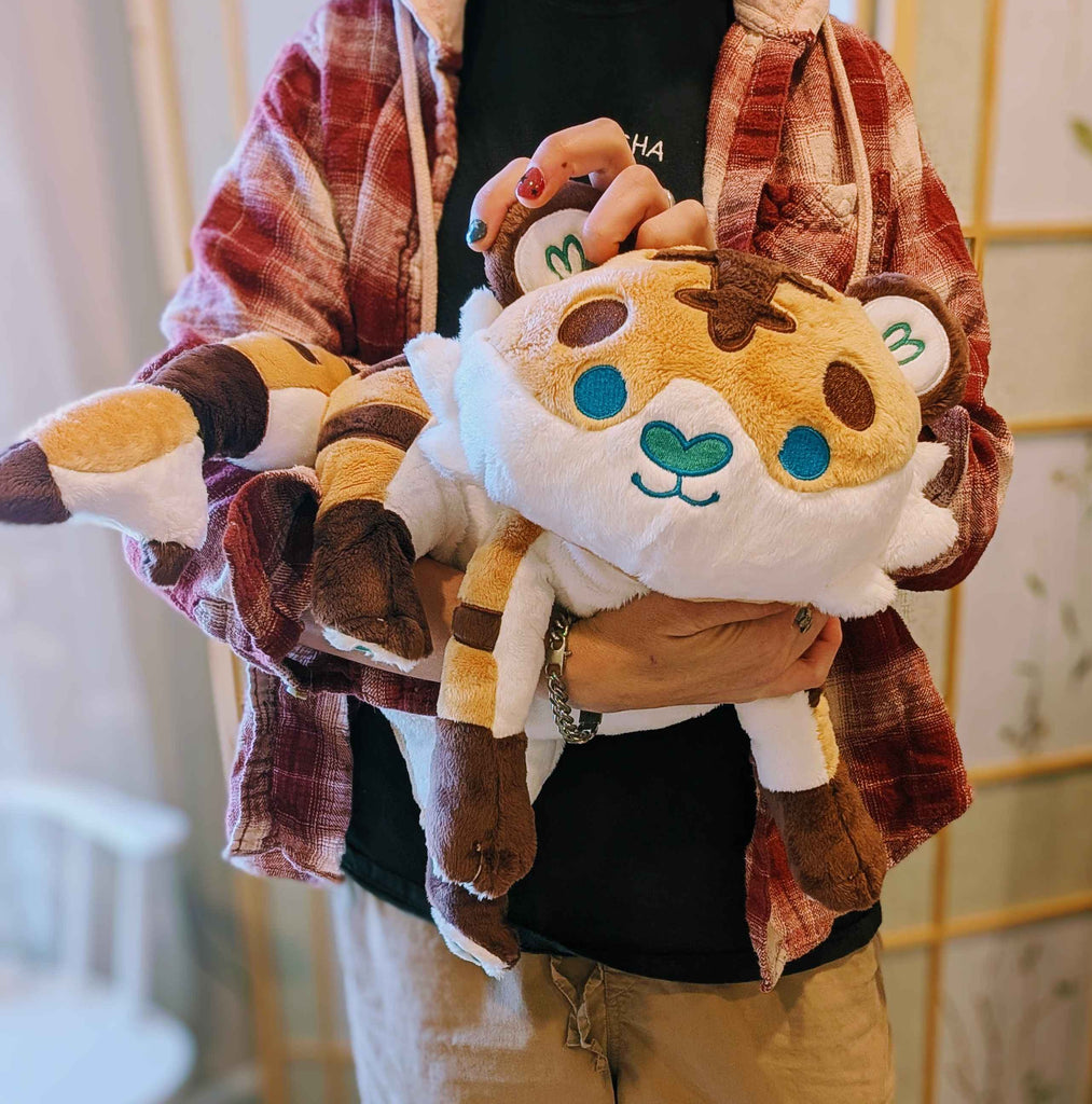 Plush toy of Cornflakes the tiger and shark hybrid being held by a person