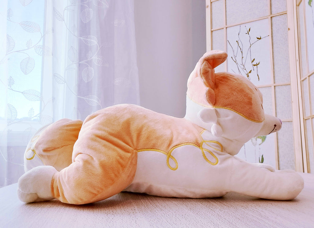 Side view of a weighted plush pillow of Sunny Pup the red border collie lying down.
