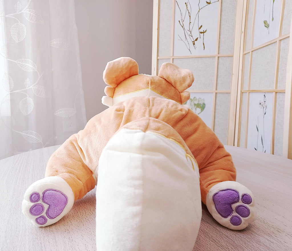 Back view of a weighted plush pillow of Sunny Pup the red border collie lying down. He has purple feet pads.
