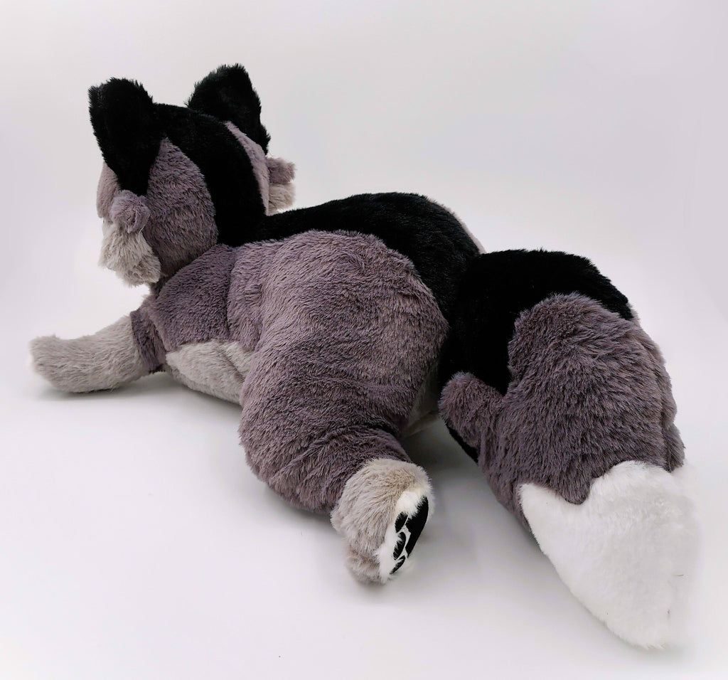 Back view of BigHugs Wolfgang weighted dark grey wolf plush pillow in a laying pose