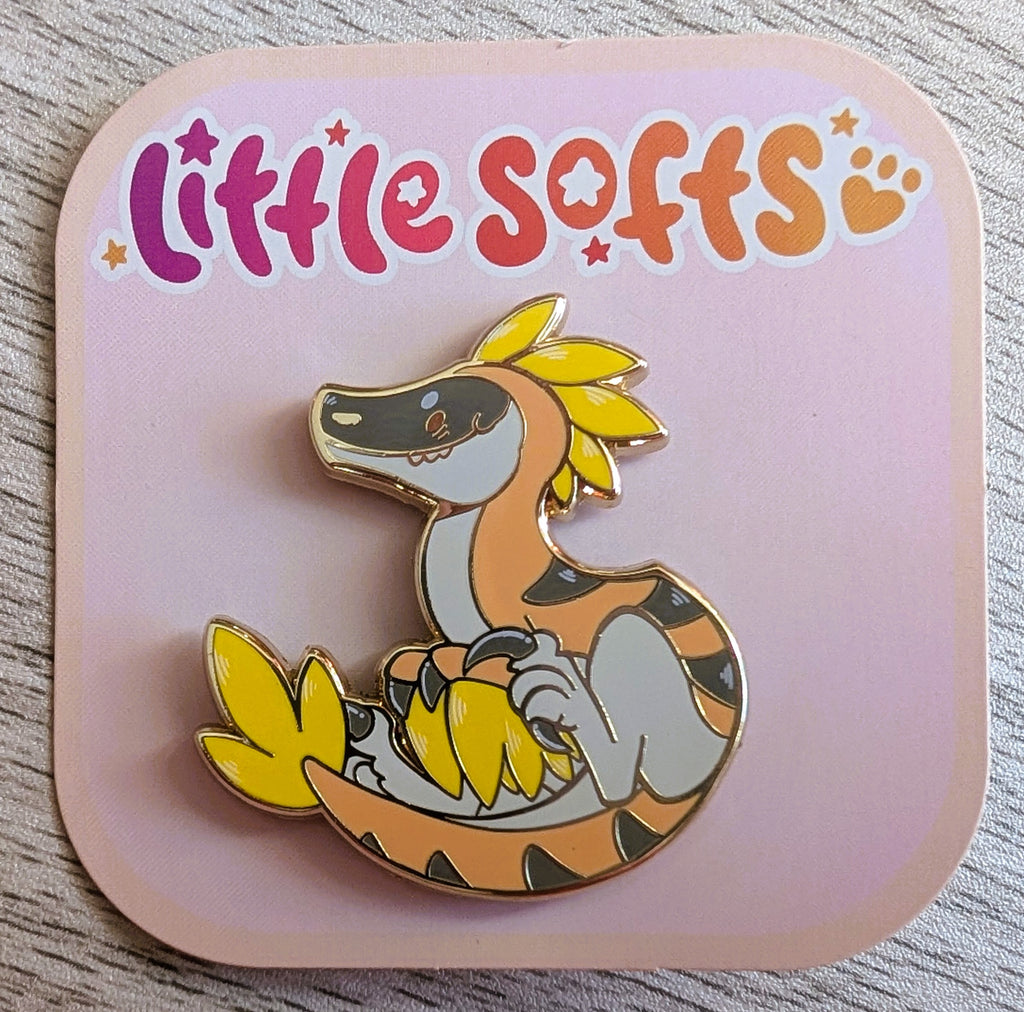 Enamel pin of Chai Latte the utahraptor who is light brown and yellow