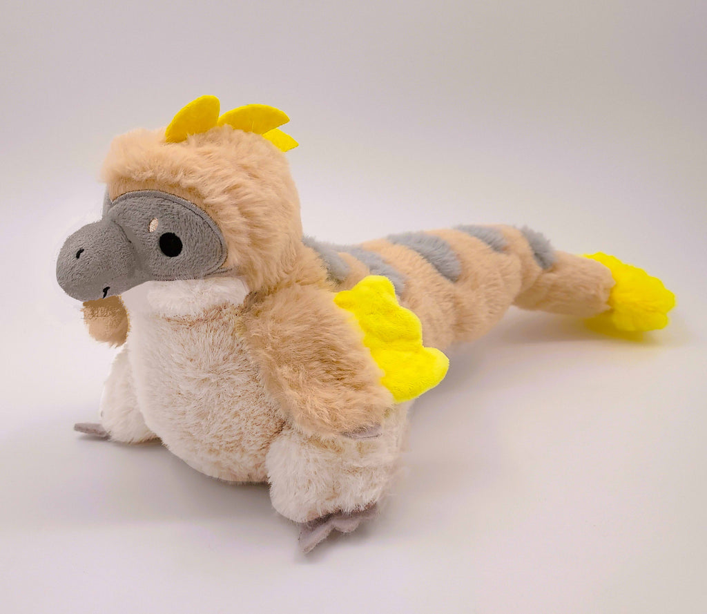 Plush toy of Chai Latte the grey, yellow, and light brown utahraptor