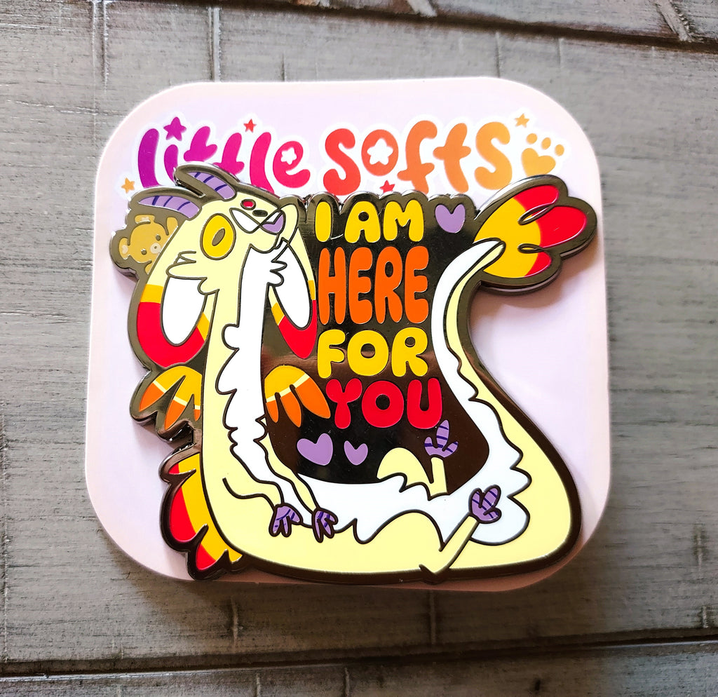 Enamel pin of Charmy the trauma dragon and teddy bear that says "I am here for you"