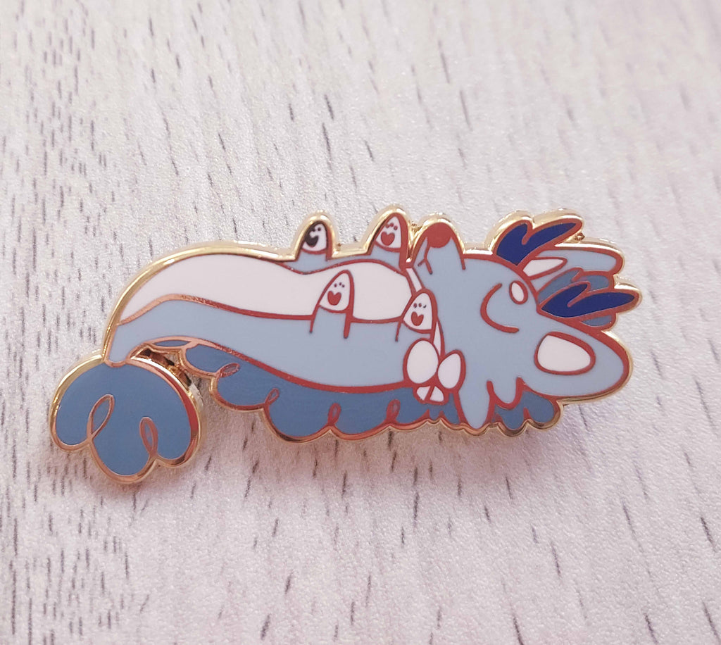 Enamel pin of Cloud the blue dragon lying on his back and sleeping