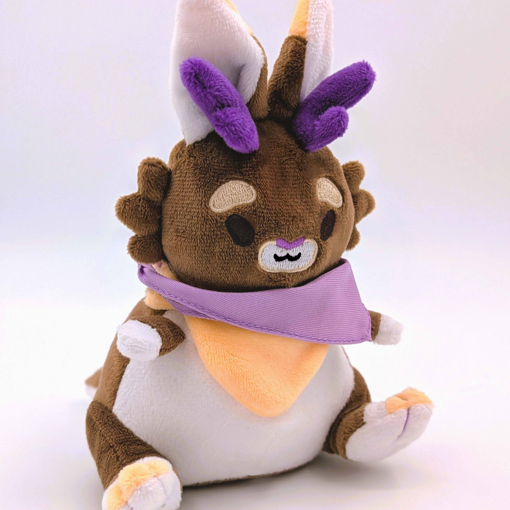 Plush toy of a jackalope with a brown and white design, purple accents, and a white background