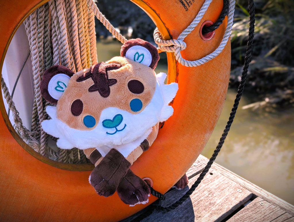 Plush toy of Cornflakes the tiger and shark hybrid resting in an orange lifesaver