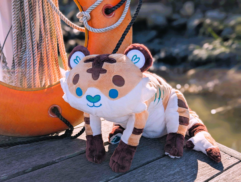 Plush toy of Cornflakes the tiger and shark hybrid resting on a dock next to an orange lifesaver