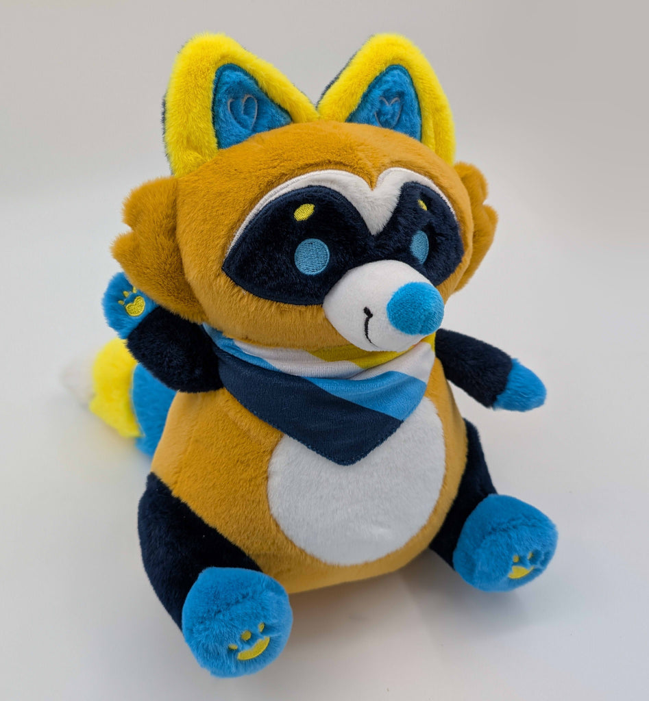 Plush toy of Mango the blue, orange, yellow raccoon