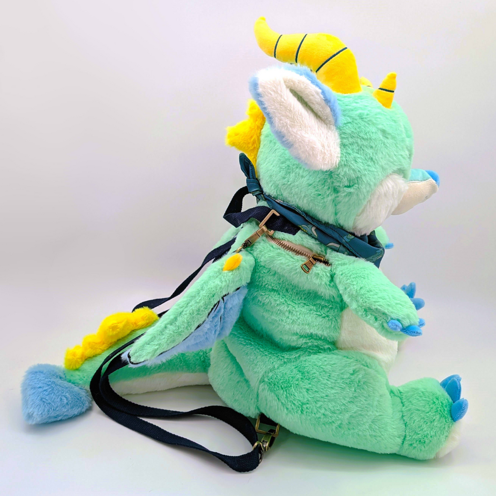 Side view of a plush backpack of a green dragon