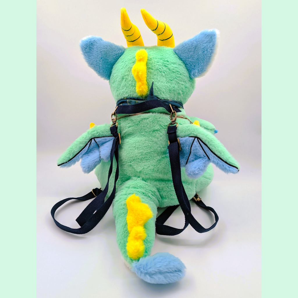 Back view of a plush backpack of a green dragon