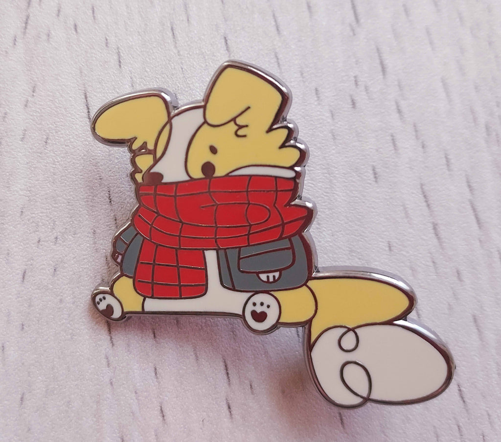 Enamel pin of Sunny Pup the red border collie wearing a red plaid scarf and denim jacket