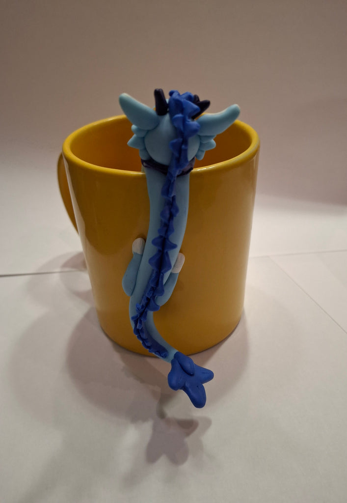 The back of a sculpture of a blue dragon posed on a yellow mug