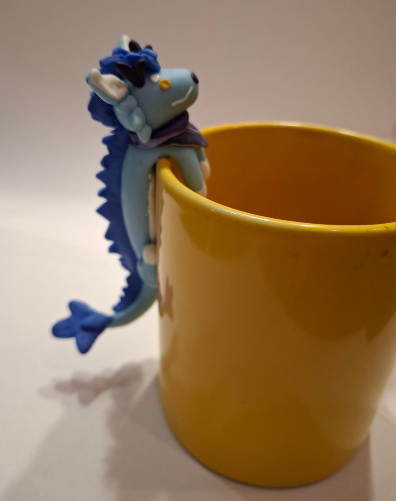 Sculpture of a blue dragon posed on a yellow mug
