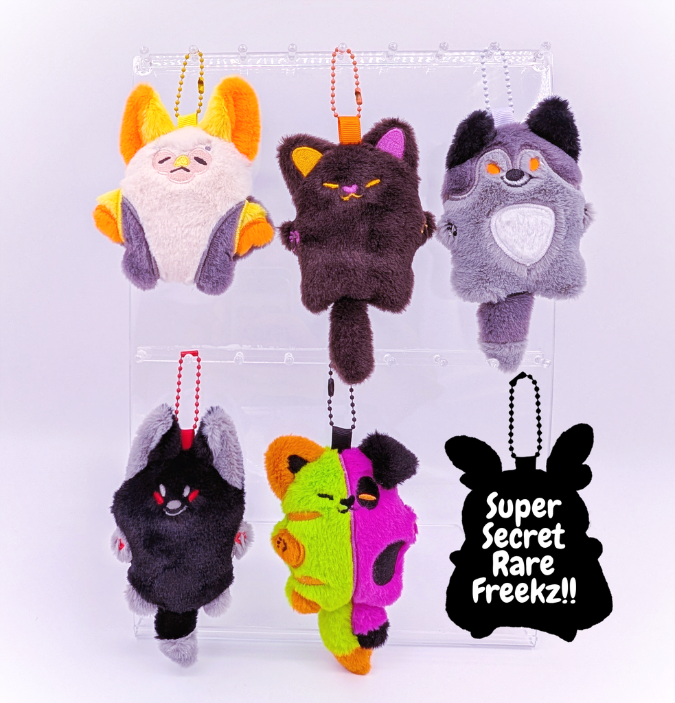 Halloween themed mini plush including a bat with yellow ears, a black fox, a grey wolf with orange eyes, a black cat with purple and orange face, and a half purple puppy, half green kitty monster, as well as a mystery secret character