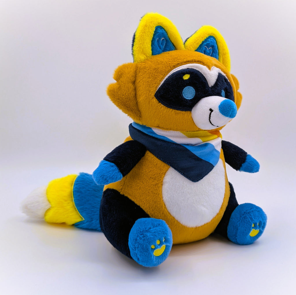 Plush toy of Mango the orange, blue, yellow raccoon