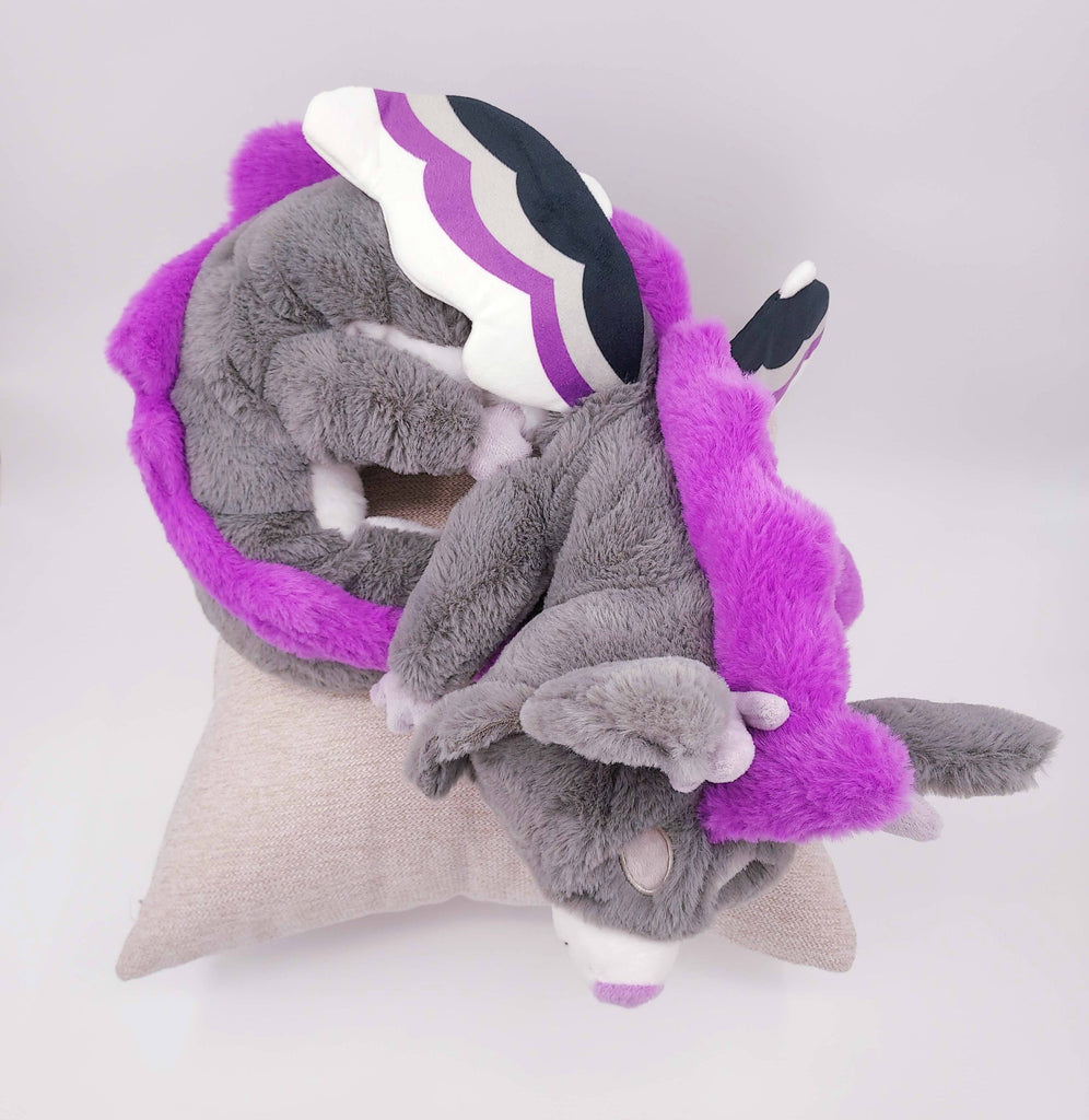 Large plush of Marshmallow the purple, black, white, and grey dragon, sleeping on a pillow.