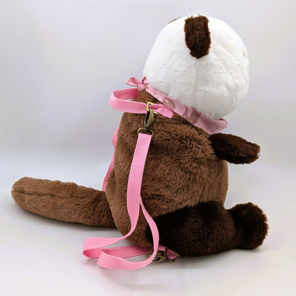Side view of a plush backpack of an otter with pink straps