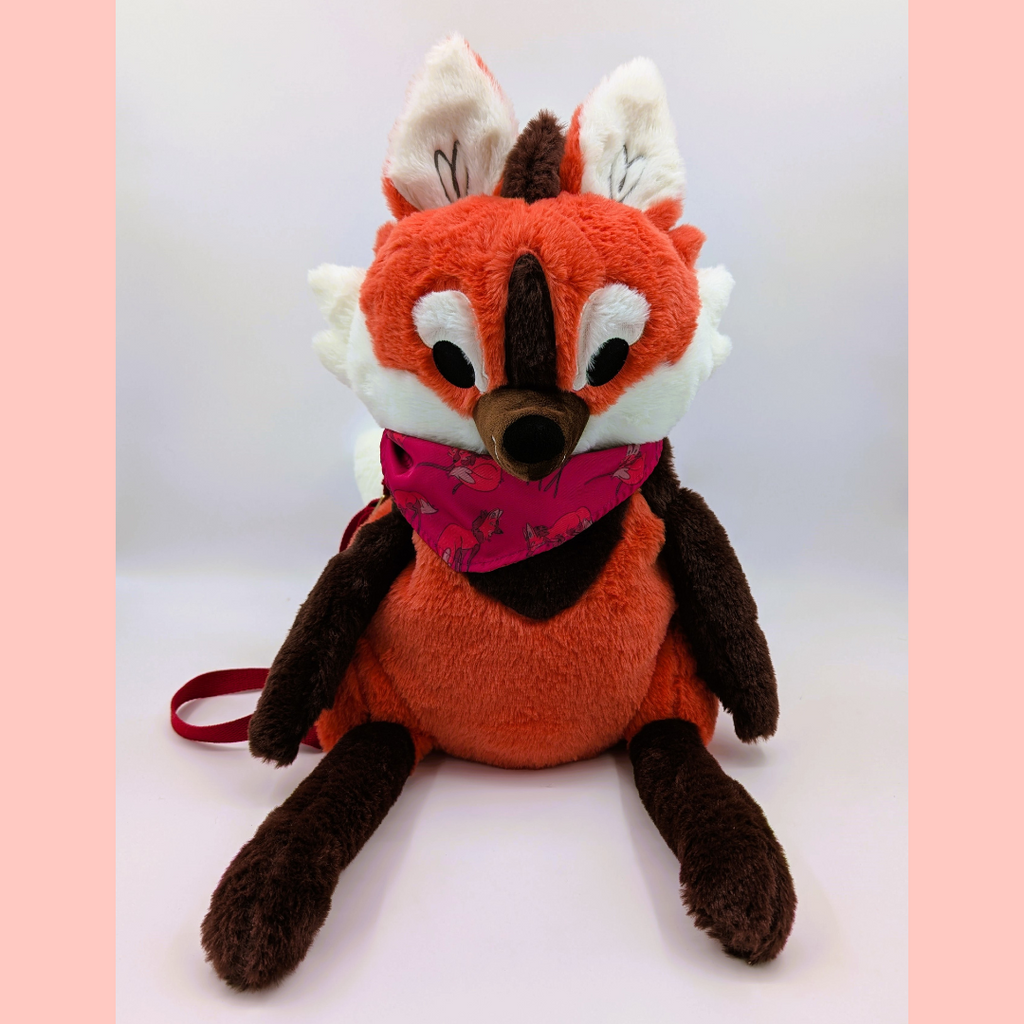 Plush toy maned wolf with a pink bandana on a white background