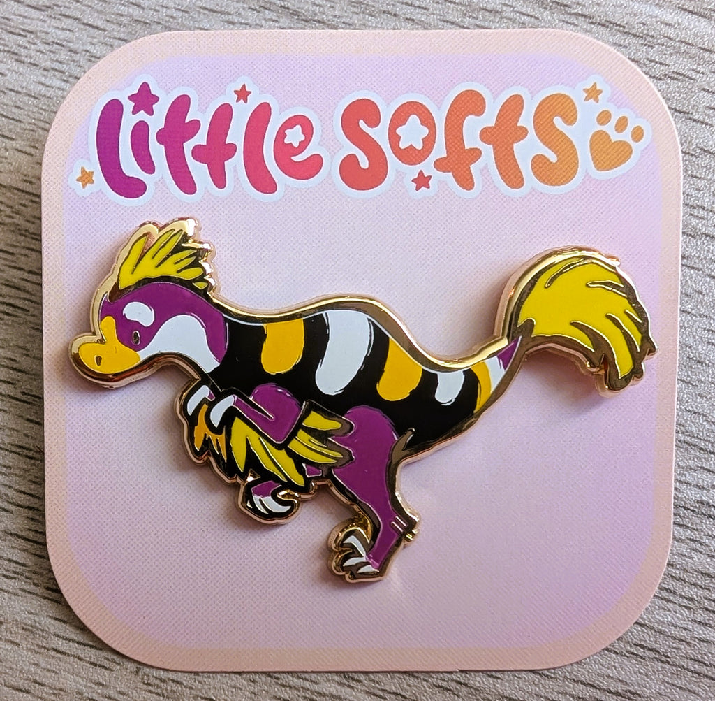 Enamel pin of Passionfruit the black, white, purple, and yellow utahraptor