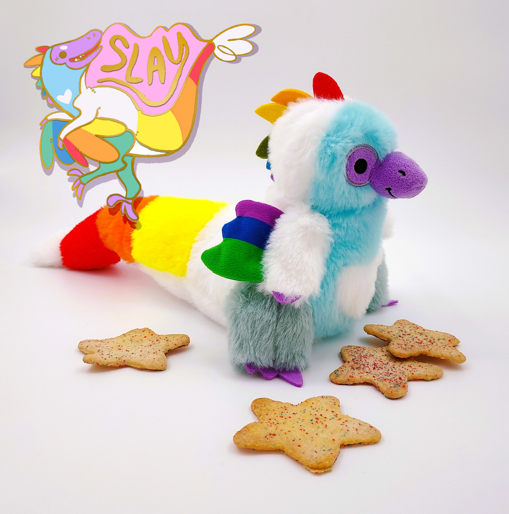 Plush toy of Sugar Cookie the Rainbow Utahraptor dinosaur with enamel pin of Sugar Cookie that says Slay and sugar cookies with sprinkles