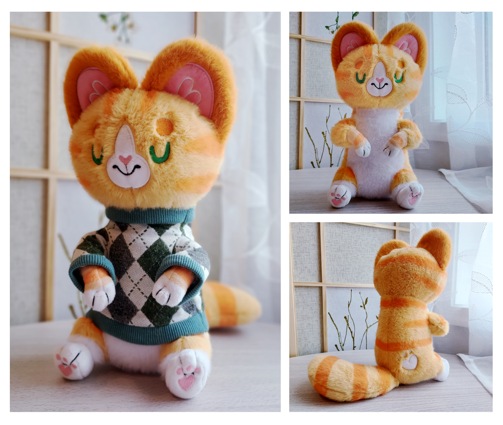 Front and back views of plush of Cheese the orange cat wearing a green argyle sweater
