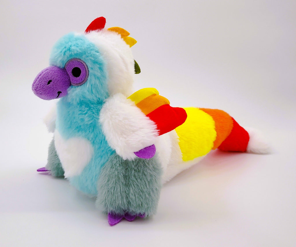 Plush toy of Sugar Cookie the Rainbow Utahraptor dinosaur