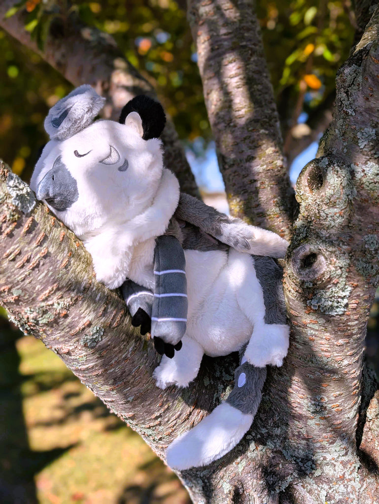 Plush toy of Sesame the grey and white gryphon resting in a tree 