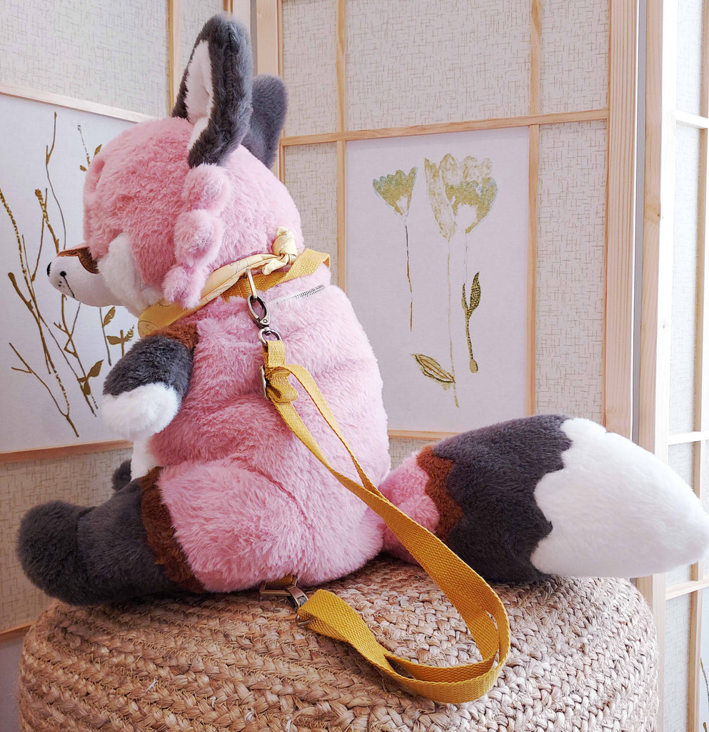 Side view of a plush backpack of Chiffon the fox wearing a yellow bandana, with yellow backpack straps
