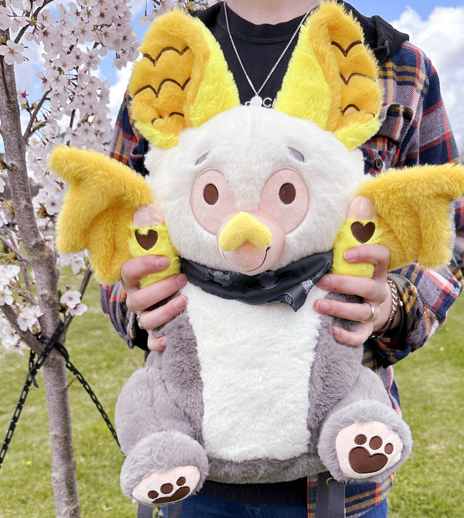 Person holding a plush backpack of Lemon the bat while standing outside