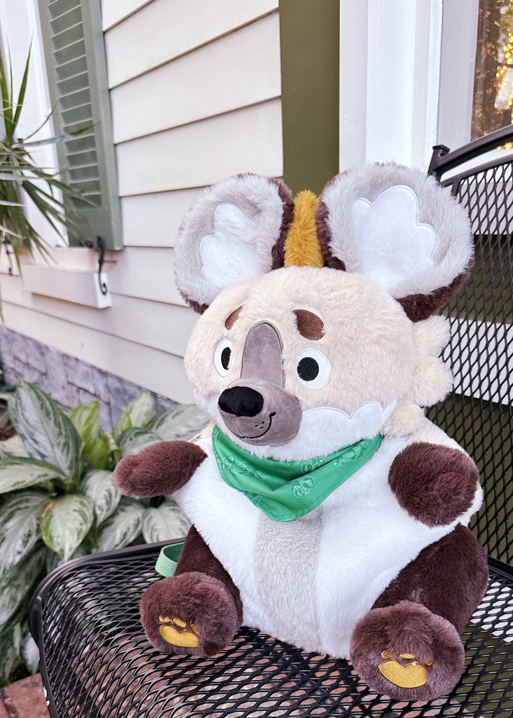 Plush backpack of ChocoChip the hyena sitting in a chair by some plants