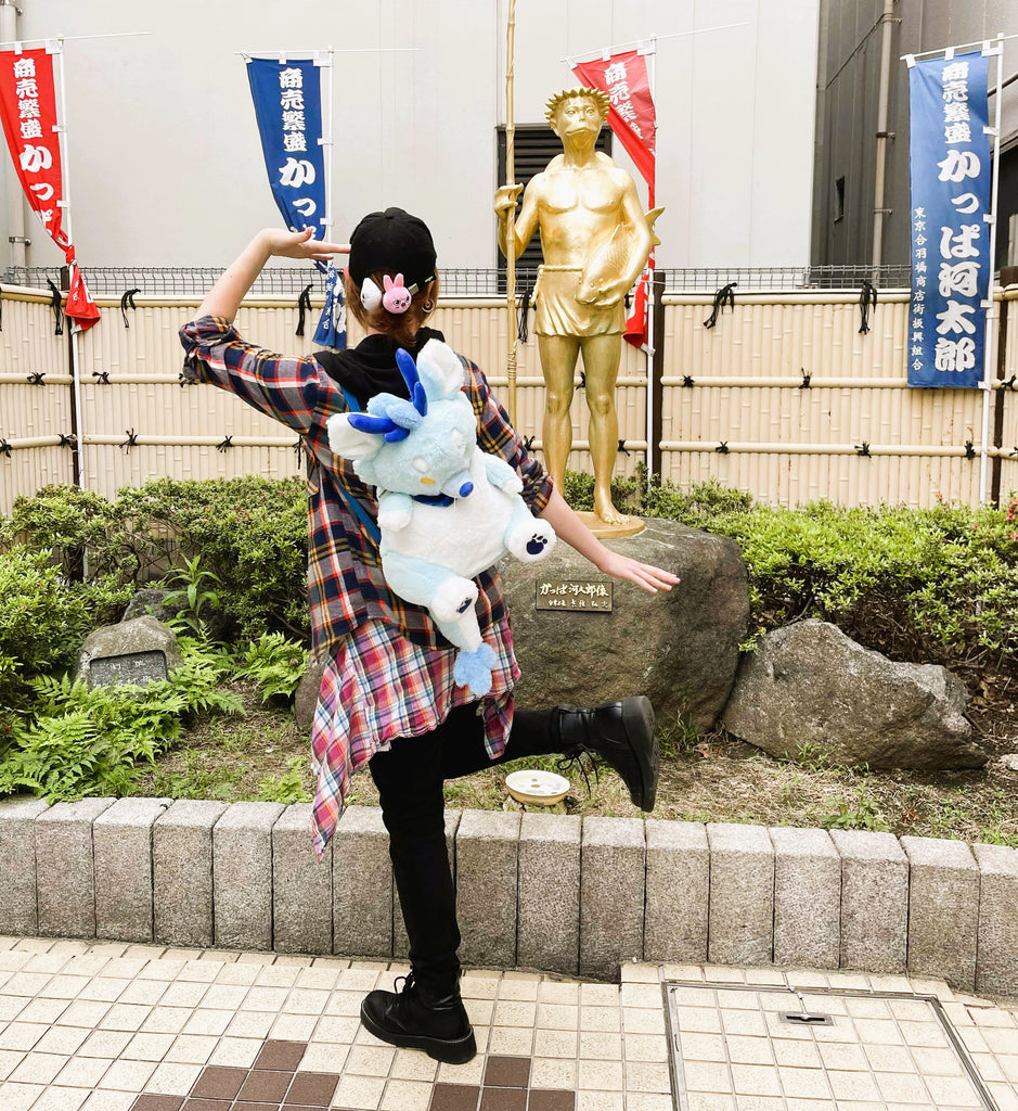 Person wearing a plush backpack of Cloud the blue dragon while striking a pose