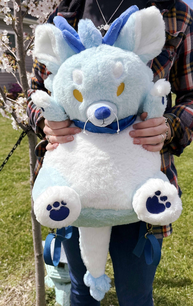 A person holding a plush backpack of Cloud the blue dragon