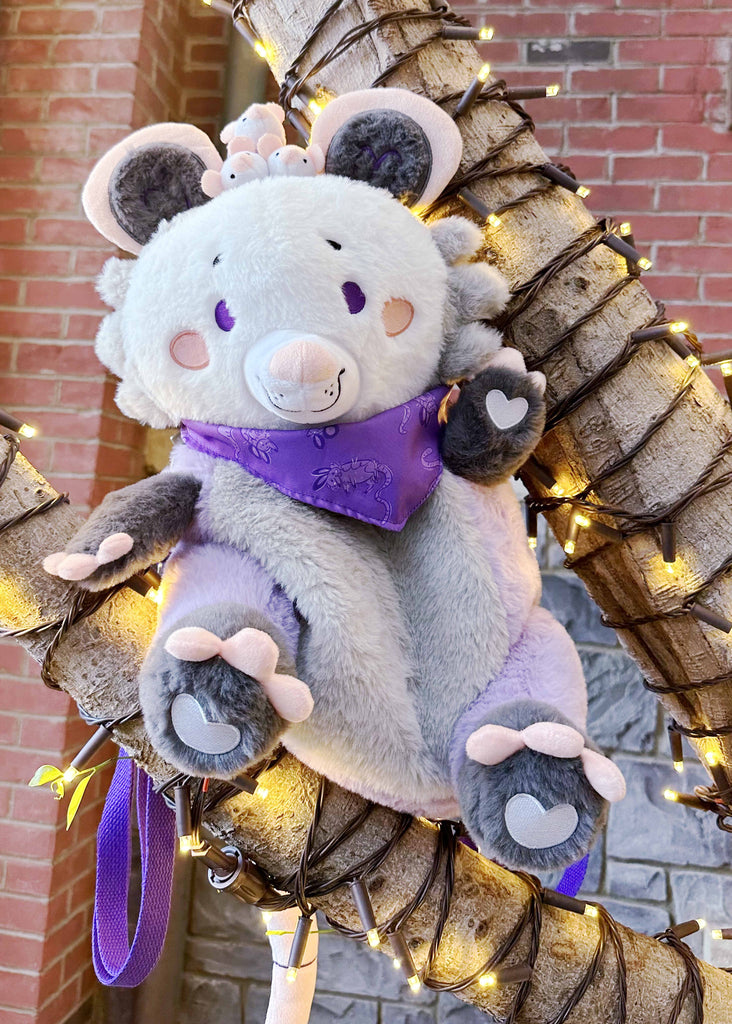 Plush backpack of Plum possum sitting in a tree decorated with lights