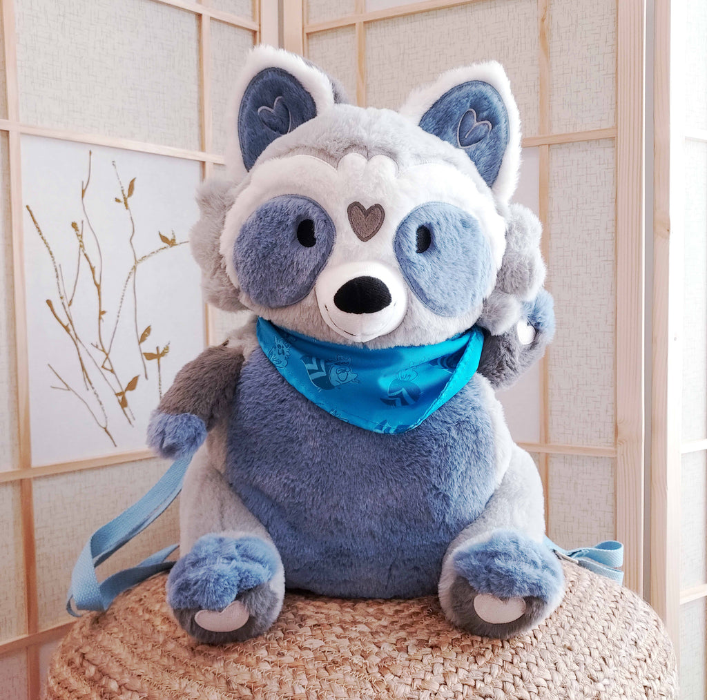 Plush backpack of Peanut the raccoon wearing a blue bandana, with blue backpack straps