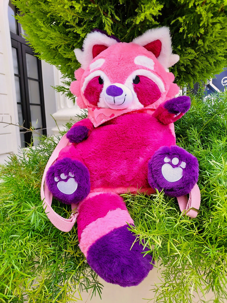 Plush backpack of Raspberry the red panda sitting in a bush