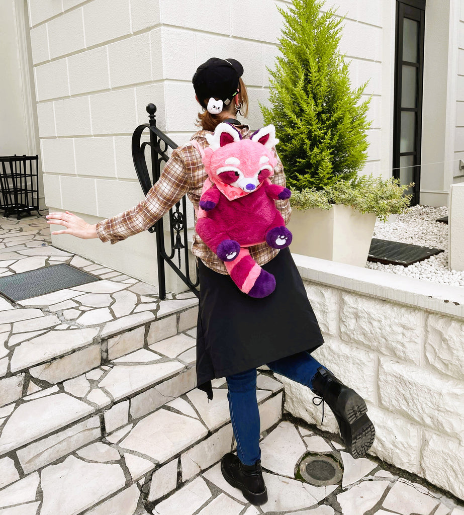 Person wearing a plush backpack of Raspberry the red panda while going up a white set of stairs