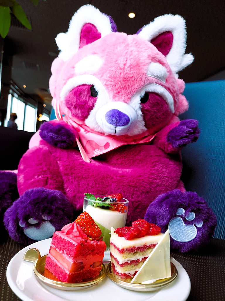 Plush backpack of Raspberry the red panda sitting with some sweets