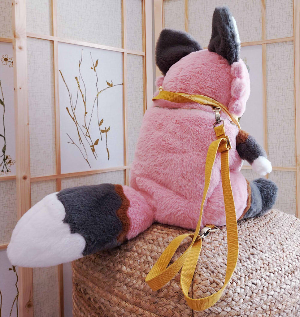 Back view of a plush backpack of Chiffon the fox wearing a yellow bandana, with yellow backpack straps
