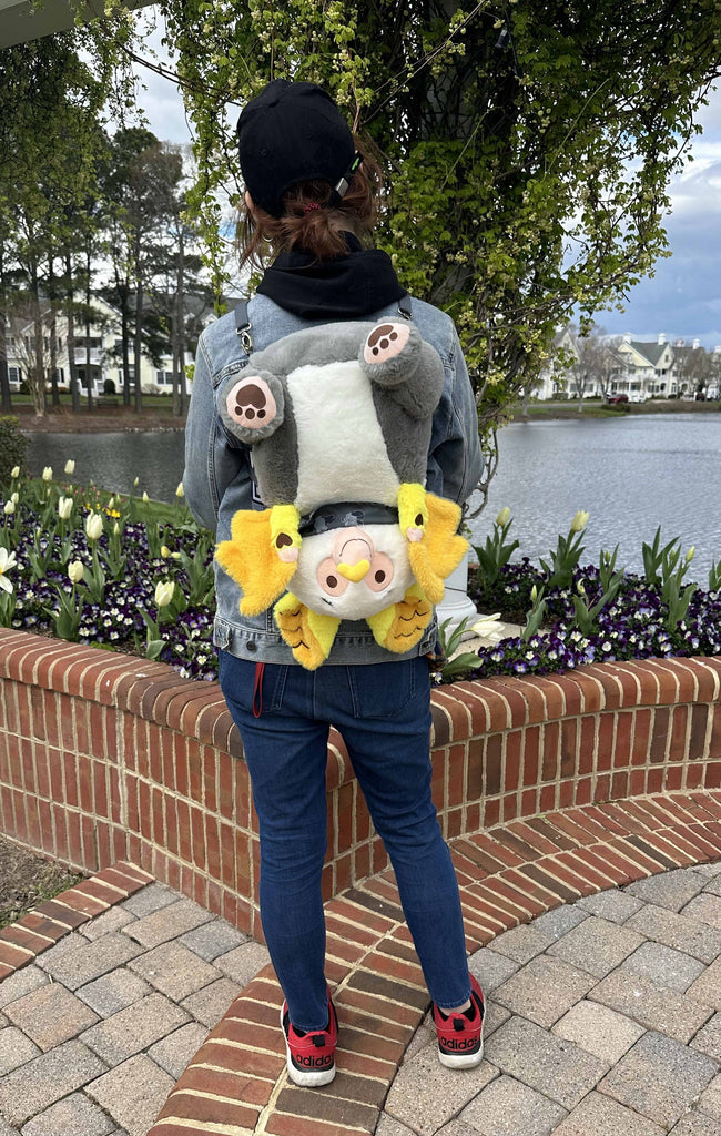 Person wearing a plush backpack of Lemon the bat upside down 