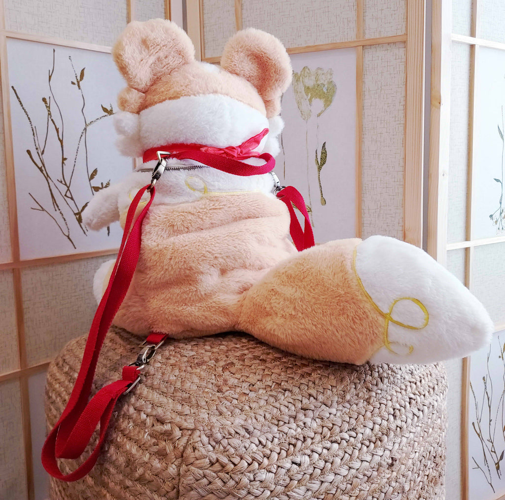 Back view of a plush backpack of Sunny Pup the red border collie wearing a red bandana, with red backpack straps